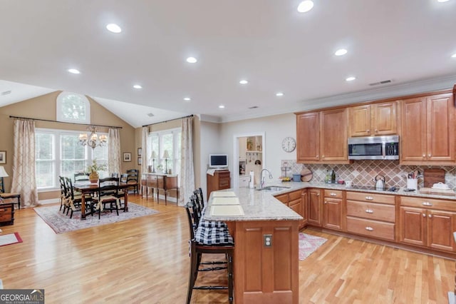 901 Providence Ln, Monroe, GA 30656 - kitchen featuring stainless steel microwave, a sink, a peninsula, light stone countertops, and light wood-type flooring