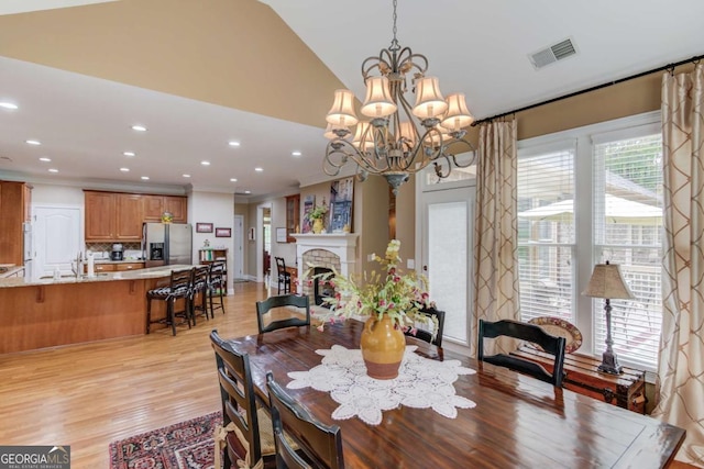 901 Providence Ln, Monroe, GA 30656 - dining area featuring recessed lighting, light wood-type flooring, a chandelier, vaulted ceiling, and a fireplace