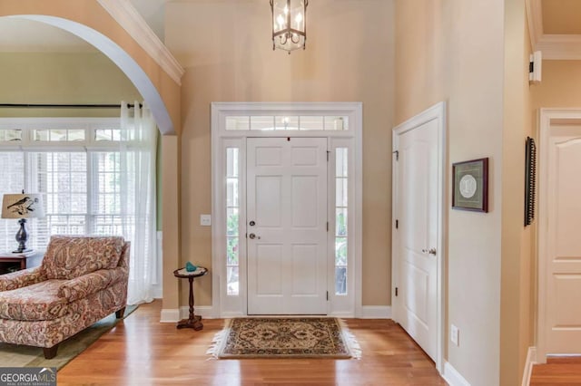 901 Providence Ln, Monroe, GA 30656 - foyer entrance featuring light wood finished floors, baseboards, arched walkways, crown molding, and a towering ceiling