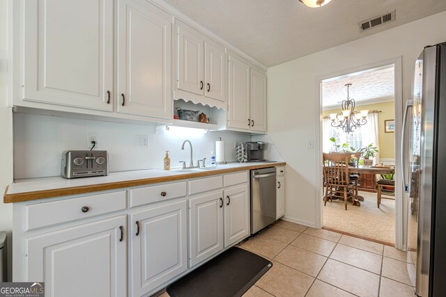 435 Flowering Trl, Grayson, GA 30017 - kitchen with appliances with stainless steel finishes, white cabinets, a chandelier, and light countertops