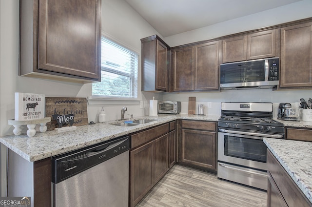 79 Mercer Ln, Cartersville, GA 30120 - kitchen featuring stainless steel appliances, a sink, light wood-style flooring, dark brown cabinetry, and light stone countertops