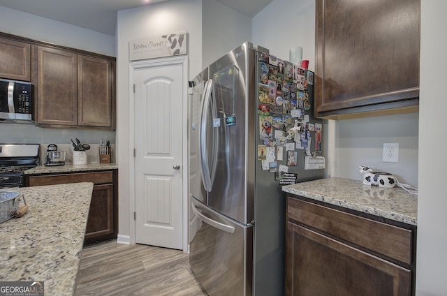 79 Mercer Ln, Cartersville, GA 30120 - kitchen with appliances with stainless steel finishes, dark brown cabinetry, light wood-style flooring, and light stone countertops