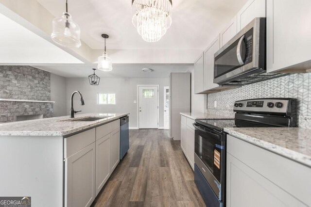 108 Holly St, Warner Robins, GA 31093 - kitchen featuring stainless steel appliances, a sink, decorative backsplash, dark wood-style flooring, and light stone counters
