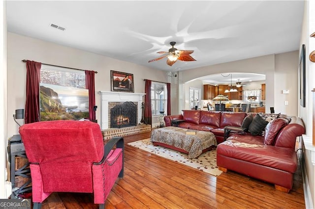 1070 Cureton Dr, Austell, GA 30106 - living room featuring arched walkways, ceiling fan, hardwood / wood-style floors, and a brick fireplace