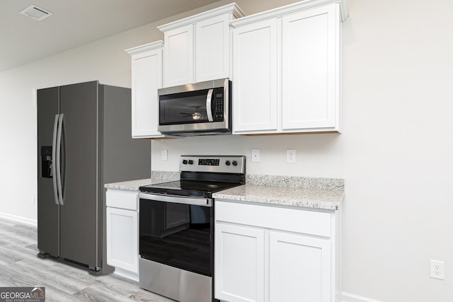 305 Limestone Circcle, Conyers, GA 30013 - kitchen with stainless steel appliances, light wood-type flooring, white cabinetry, and light stone counters