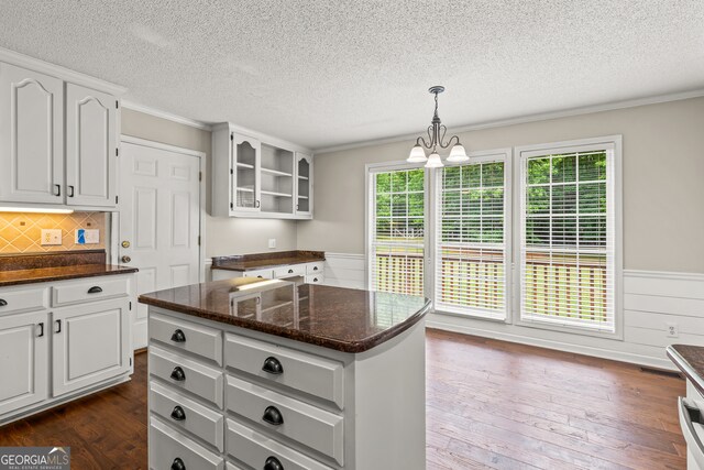 220 Drumcliff Ct, Tyrone, GA 30290 - kitchen with a textured ceiling, dark wood-style floors, glass insert cabinets, a wainscoted wall, and dark stone countertops