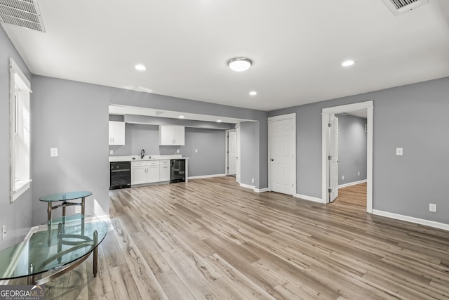220 Drumcliff Ct, Tyrone, GA 30290 - unfurnished living room with beverage cooler, bar with sink, baseboards, light wood-style floors, and recessed lighting
