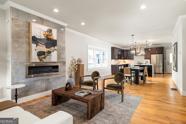 1354 Mcpherson Ave SE, Atlanta, GA 30316 - living room featuring light wood-style flooring, a chandelier, recessed lighting, a fireplace, and ornamental molding