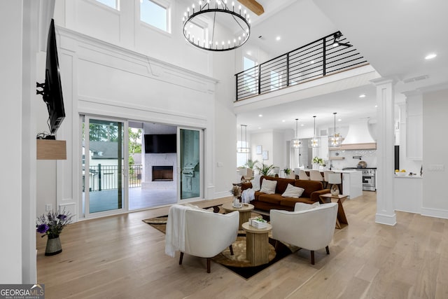 2631 Sardis Way, Buford, GA 30519 - living room featuring a high ceiling, a fireplace, light wood finished floors, a chandelier, and baseboards