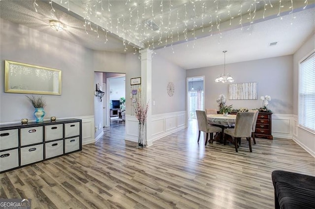 2908 Cottesford Way, Smyrna, GA 30080 - dining space featuring wood finished floors, a decorative wall, a chandelier, a wainscoted wall, and decorative columns