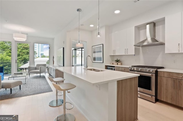 775 Juniper St NE Unit 405, Atlanta, GA 30308 - kitchen with wall chimney range hood, stainless steel range with gas stovetop, a sink, light wood-type flooring, and light countertops