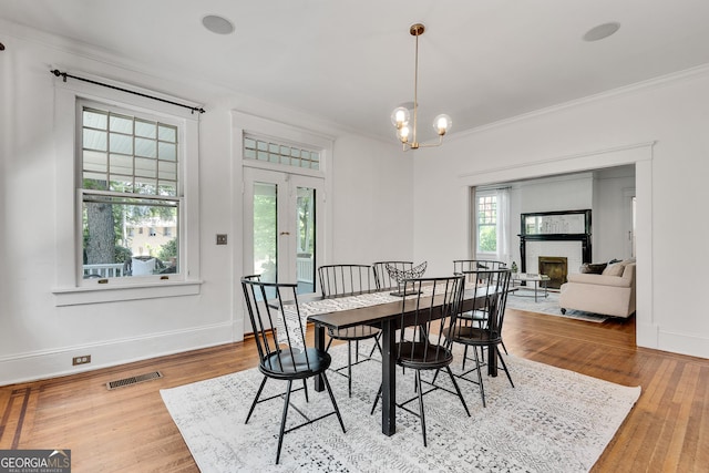 1157 Alta Ave NE, Atlanta, GA 30307 - dining space with crown molding, baseboards, a fireplace, wood finished floors, and a chandelier