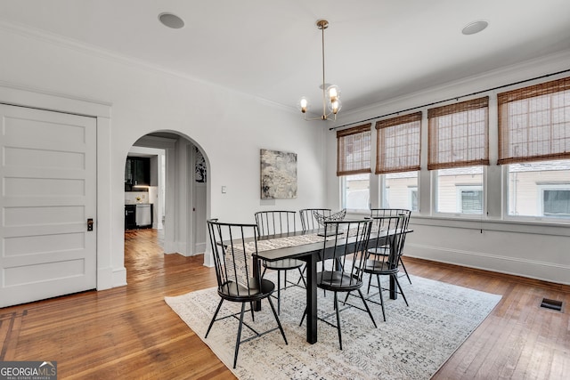 1157 Alta Ave NE, Atlanta, GA 30307 - dining space featuring arched walkways, crown molding, wood-type flooring, baseboards, and a chandelier