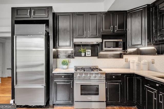 1157 Alta Ave NE, Atlanta, GA 30307 - kitchen with high quality appliances, under cabinet range hood, dark cabinets, decorative backsplash, and light wood-style floors