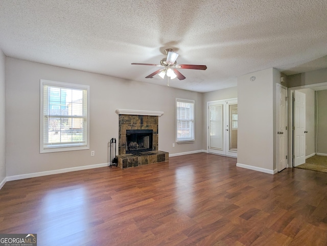 2918 Pavia Cir, Austell, GA 30106 - unfurnished living room featuring a ceiling fan, healthy amount of natural light, wood finished floors, a stone fireplace, and a textured ceiling