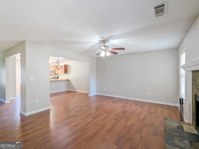 2918 Pavia Cir, Austell, GA 30106 - unfurnished living room featuring a chandelier, a ceiling fan, a tile fireplace, wood finished floors, and a textured ceiling