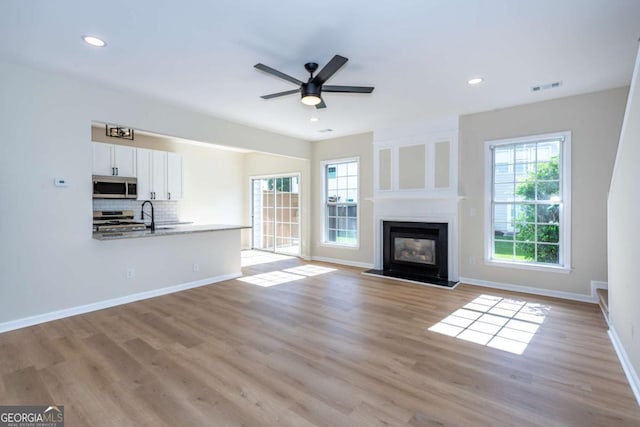 2915 Commonwealth Cir, Alpharetta, GA 30004 - unfurnished living room featuring light wood finished floors, ceiling fan, a large fireplace, baseboards, and recessed lighting