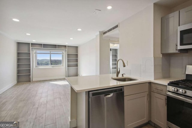 2285 Peachtree Rd NE, Atlanta, GA 30309 - kitchen featuring appliances with stainless steel finishes, a sink, light wood finished floors, a peninsula, and light countertops