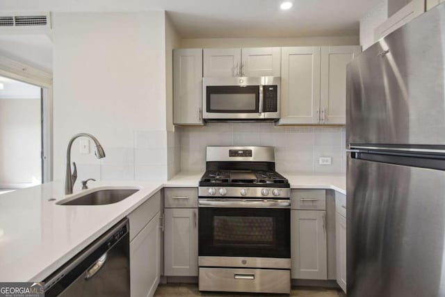 2285 Peachtree Rd NE, Atlanta, GA 30309 - kitchen with stainless steel appliances, a sink, light countertops, gray cabinetry, and decorative backsplash