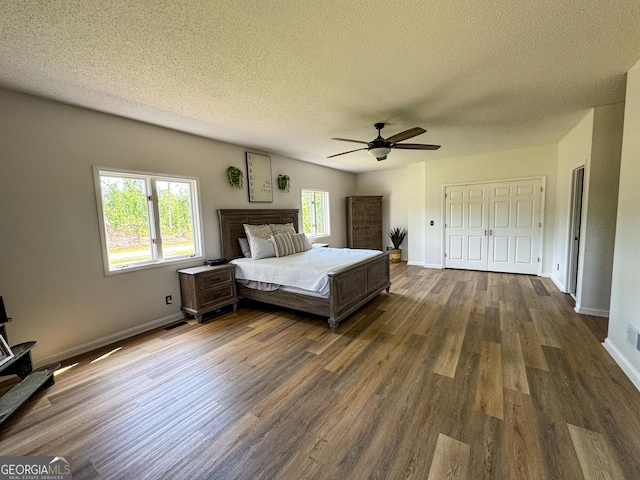 134 Roy Dean Rd, Buchanan, GA 30113 - bedroom with dark wood finished floors, a textured ceiling, baseboards, a closet, and a ceiling fan