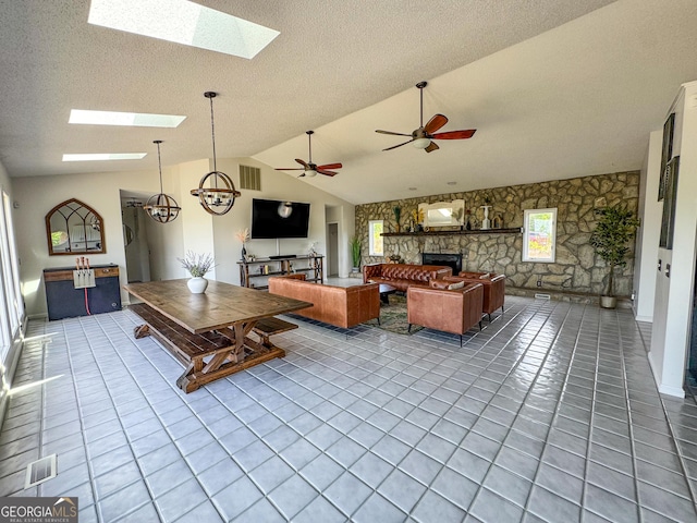 134 Roy Dean Rd, Buchanan, GA 30113 - tiled living room featuring a stone fireplace, a skylight, vaulted ceiling, a textured ceiling, and ceiling fan