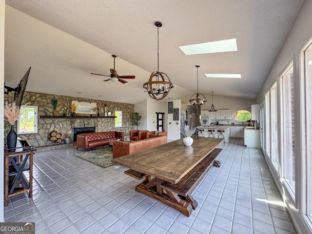 134 Roy Dean Rd, Buchanan, GA 30113 - dining space featuring vaulted ceiling, a stone fireplace, light tile patterned floors, a chandelier, and a skylight