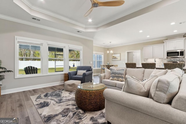 194 Pistachio Ln, Kingsland, GA 31548 - living room with a chandelier, wood finished floors, a tray ceiling, baseboards, and ornamental molding