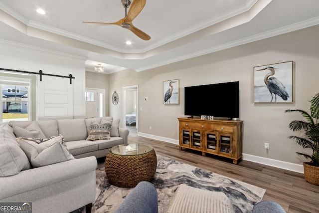 194 Pistachio Ln, Kingsland, GA 31548 - living area featuring a tray ceiling, ceiling fan, a barn door, wood finished floors, and crown molding