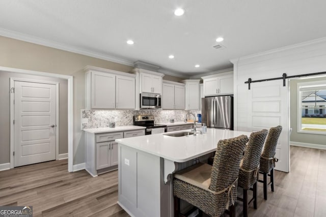 194 Pistachio Ln, Kingsland, GA 31548 - kitchen featuring appliances with stainless steel finishes, a sink, crown molding, tasteful backsplash, and a kitchen bar