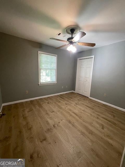 3120 Saint Andrews Cir, Duluth, GA 30096 - unfurnished bedroom with wood finished floors, baseboards, a ceiling fan, and a closet