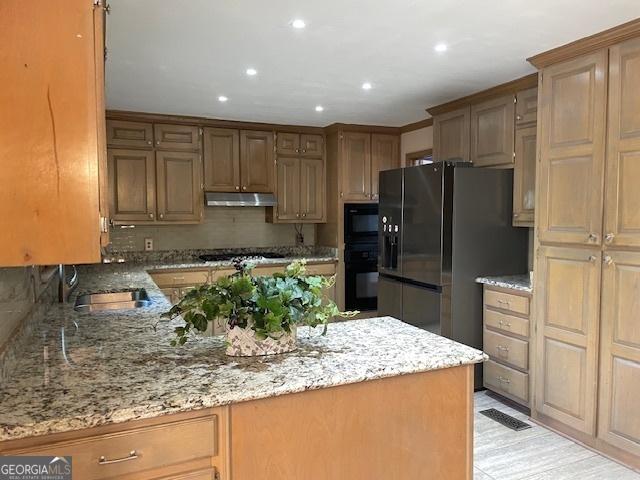 3120 Saint Andrews Cir, Duluth, GA 30096 - kitchen with under cabinet range hood, freestanding refrigerator, a sink, light stone counters, and recessed lighting