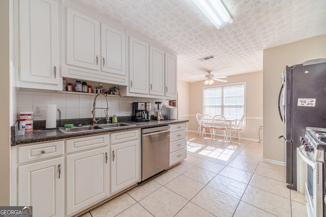704 Stonecrest Ln, Loganville, GA 30052 - kitchen with dishwasher, a sink, white gas stove, baseboards, and white cabinetry