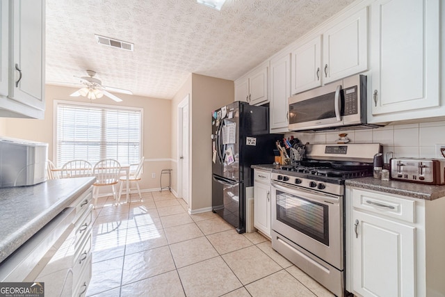 704 Stonecrest Ln, Loganville, GA 30052 - kitchen featuring appliances with stainless steel finishes, white cabinetry, a ceiling fan, baseboards, and light tile patterned floors