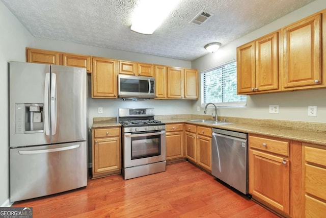 744 Martin Rd, Stone Mountain, GA 30088 - kitchen with appliances with stainless steel finishes, light wood finished floors, and a textured ceiling
