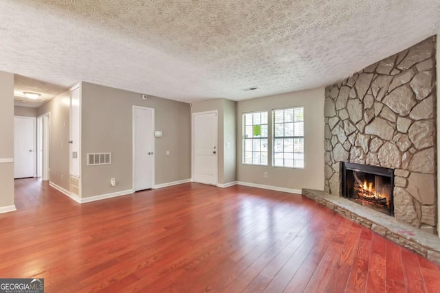 744 Martin Rd, Stone Mountain, GA 30088 - unfurnished living room with a textured ceiling, a fireplace, and wood finished floors