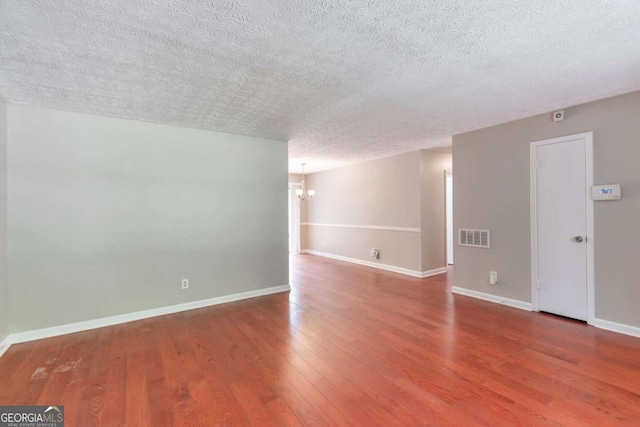 744 Martin Rd, Stone Mountain, GA 30088 - spare room featuring a textured ceiling, a chandelier, and wood finished floors