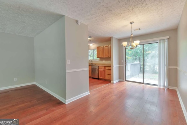 744 Martin Rd, Stone Mountain, GA 30088 - kitchen featuring stainless steel dishwasher, a chandelier, light wood-type flooring, a textured ceiling, and pendant lighting