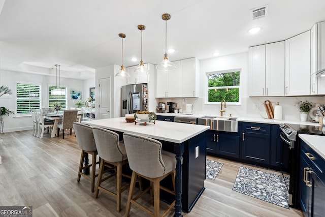6565 Nix Rd, Dawsonville, GA 30534 - kitchen featuring appliances with stainless steel finishes, blue cabinetry, a kitchen bar, a sink, and white cabinets