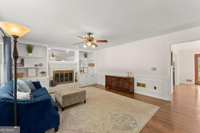 4223 N Mountain Rd NE, Marietta, GA 30066 - living area featuring a ceiling fan, crown molding, a brick fireplace, wood finished floors, and a wainscoted wall