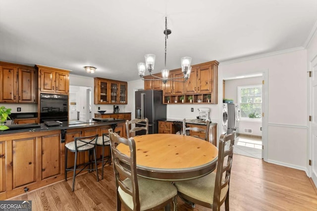 4223 N Mountain Rd NE, Marietta, GA 30066 - dining room featuring washing machine and dryer, ornamental molding, a chandelier, and light wood-style flooring