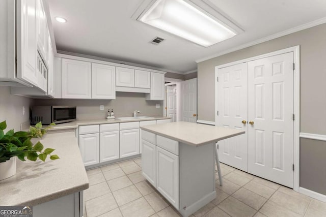 4223 N Mountain Rd NE, Marietta, GA 30066 - kitchen featuring stainless steel microwave, light countertops, white cabinets, ornamental molding, and a sink