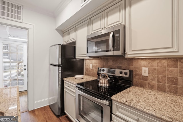 653 N Highland Ave NE Unit 5, Atlanta, GA 30306 - kitchen featuring stainless steel appliances, cream cabinets, tasteful backsplash, light wood-style flooring, and crown molding