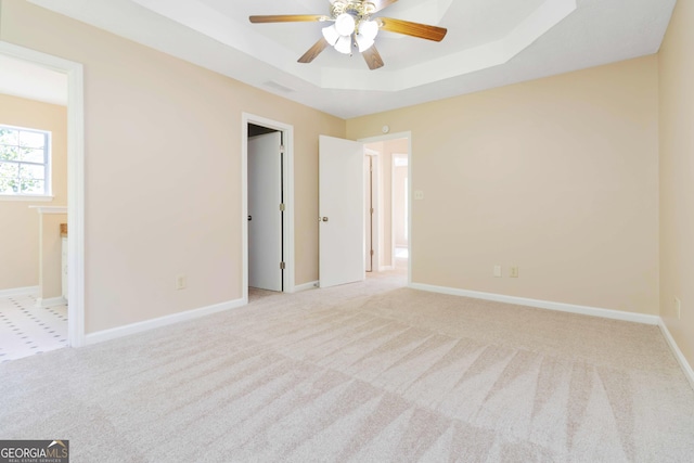 7186 Raintree Loop, Jonesboro, GA 30236 - unfurnished bedroom with a tray ceiling, carpet floors, baseboards, connected bathroom, and ceiling fan