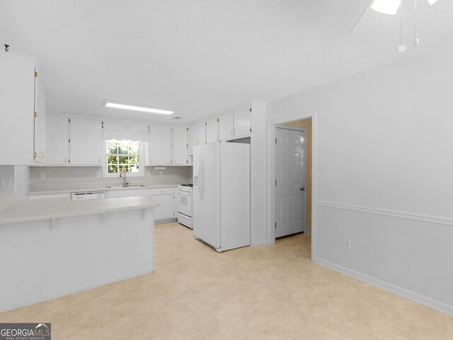 264 Keller Dr, Mcdonough, GA 30252 - kitchen with white appliances, light countertops, a peninsula, a sink, and white cabinets