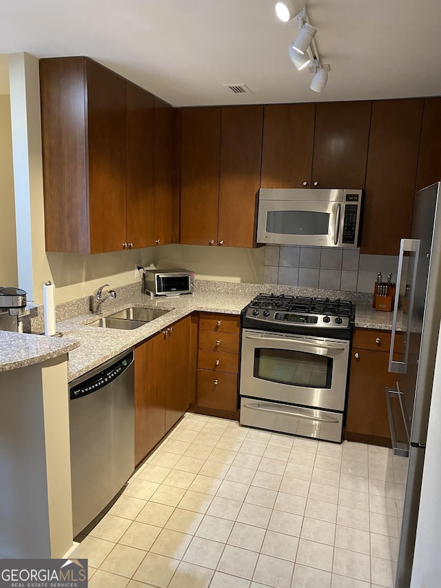 3338 Peachtree Rd NE Apt 505, Atlanta, GA 30326 - kitchen featuring appliances with stainless steel finishes, a sink, light tile patterned flooring, light stone countertops, and track lighting