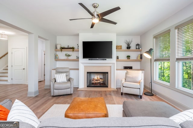 1013 Liberty Springs Dr, Woodstock, GA 30188 - living room with stairs, a ceiling fan, a lit fireplace, and light wood-type flooring