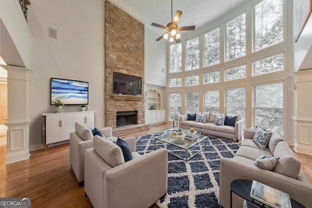 1575 Petal Pt NW, Kennesaw, GA 30152 - living room with a towering ceiling, wood finished floors, a ceiling fan, a stone fireplace, and built in features