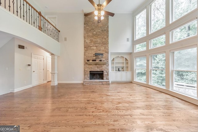 1575 Petal Pt NW, Kennesaw, GA 30152 - unfurnished living room with a high ceiling, a ceiling fan, light wood-type flooring, a stone fireplace, and baseboards