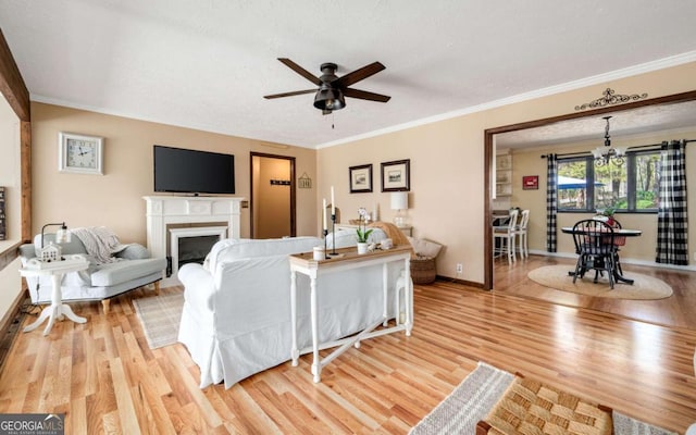 2796 County Line Rd NW, Acworth, GA 30101 - living room featuring light wood-style flooring, crown molding, a ceiling fan, a fireplace, and baseboards