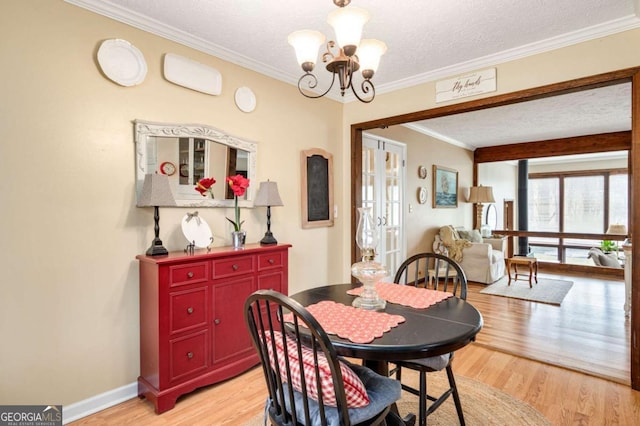 2796 County Line Rd NW, Acworth, GA 30101 - dining area featuring a chandelier, light wood-type flooring, crown molding, a textured ceiling, and baseboards